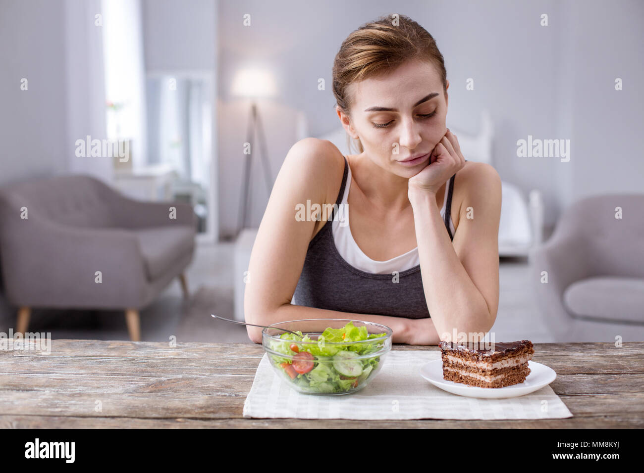 Nachdenkliche junge Frau am Kuchen suchen Stockfoto