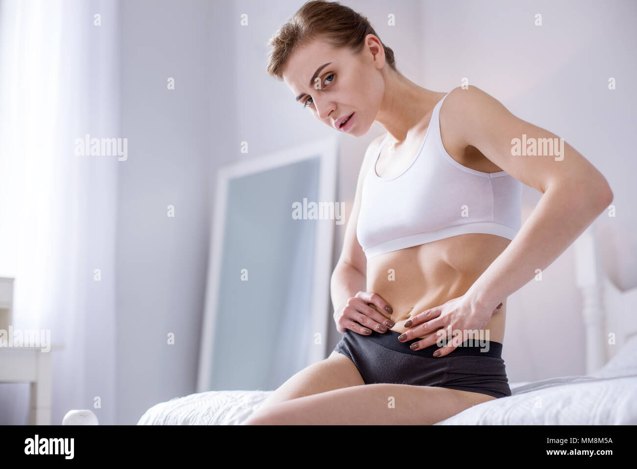 Traurig, schlanke Frau sitzt auf dem Bett Stockfoto