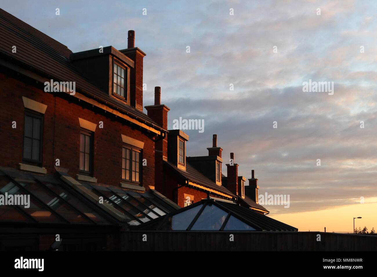 Eine Reihe von roten Backsteinhäuser spiegelt die niedrigen Abendsonne. Stockfoto