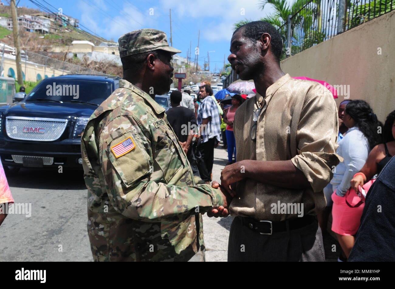 Kapitän Dion Christopher, Kaplan der Virgin Islands National Guard spricht mit Mitgliedern der Gemeinschaft stehen in der Linie für Nahrung und Wasser an einen Verteilungspunkt auf St. Thomas, Sept. 17. Der kaplan besuchte verschiedene Orte der Verteilung mit den Soldaten und Piloten nach dem Hurrikan Irma zu beten. Stockfoto