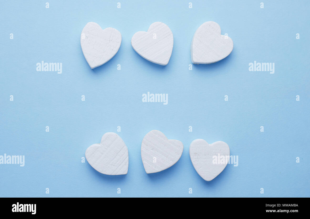 Holz- Herzen in einer Reihe über blauen Hintergrund mit negativen Raum organisiert, Ansicht von oben Stockfoto