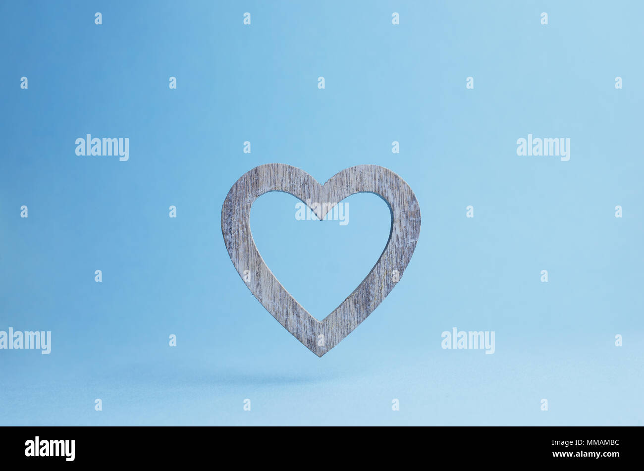 Holz- Herz über blauen Hintergrund fällt mit negativen Raum Stockfoto