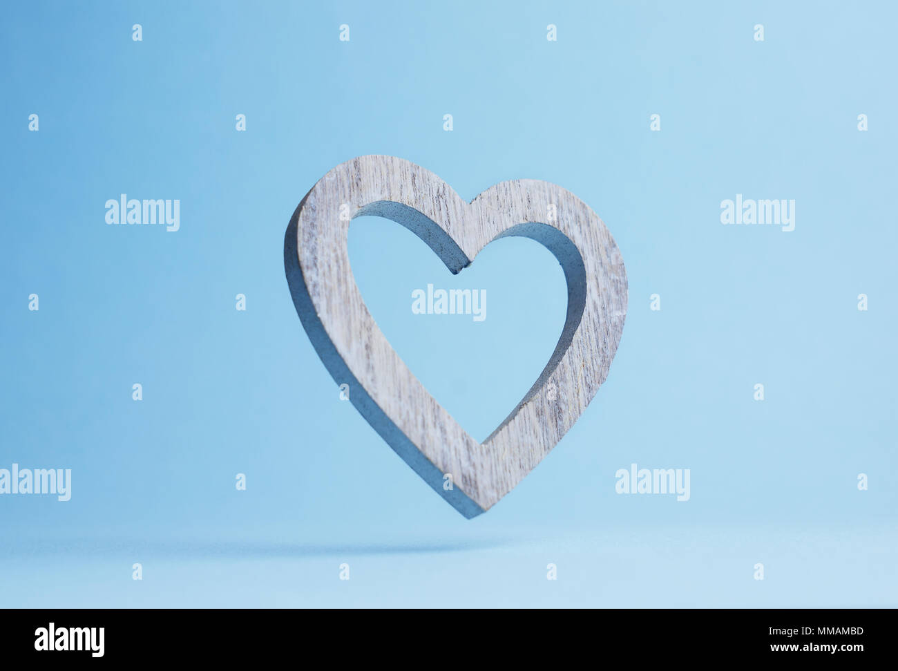 Holz- Herz über blauen Hintergrund fällt mit negativen Raum Stockfoto