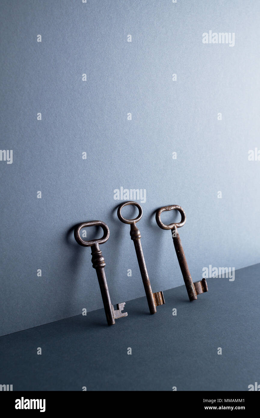 Vintage Keys lehnte sich gegen Dunkelblauer Hintergrund mit negativen Raum Stockfoto