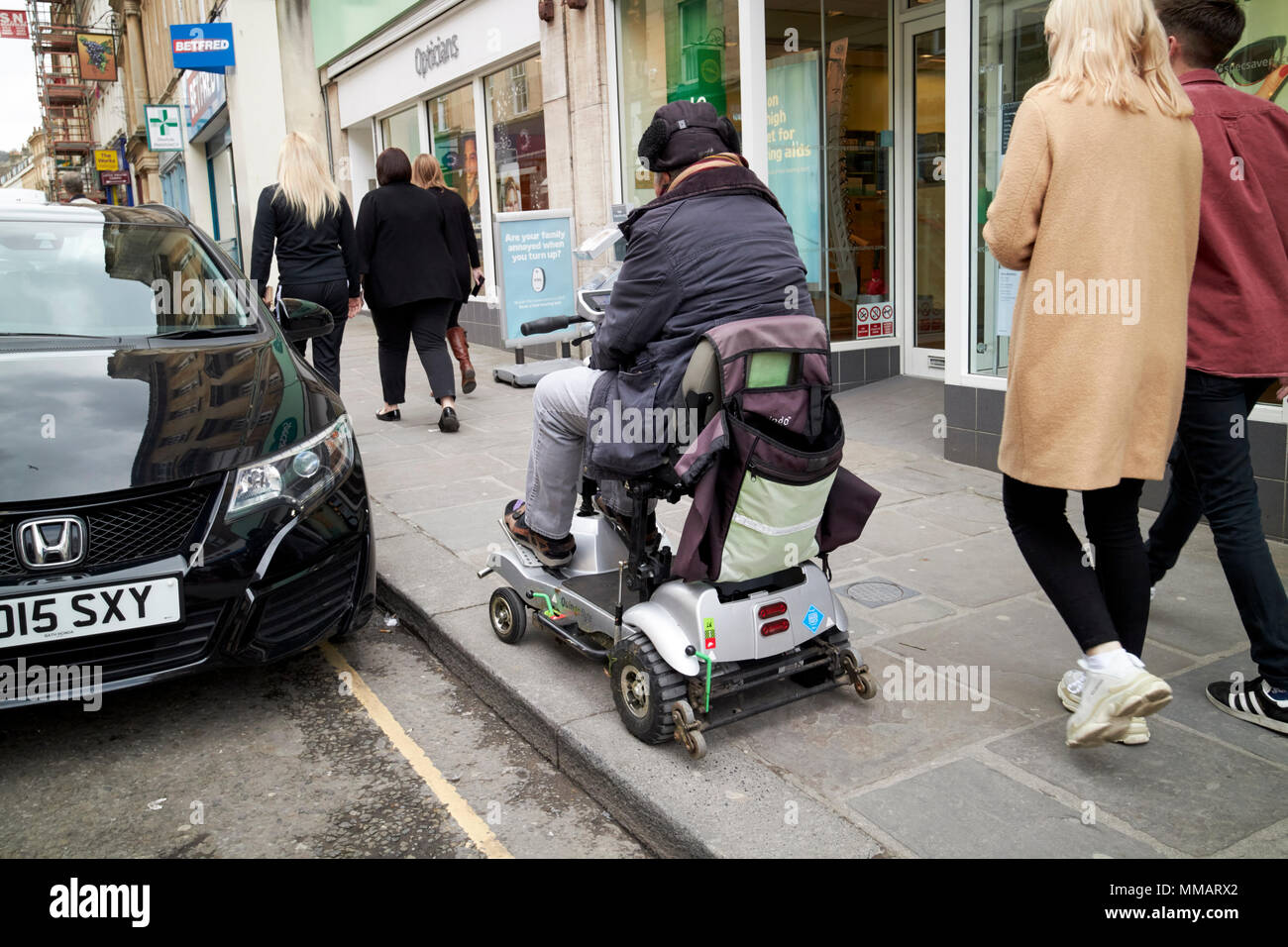 Der Mensch, er reitet Behinderung scooter von befestigten Straßen im Stadtzentrum, in der Badewanne England Großbritannien Stockfoto