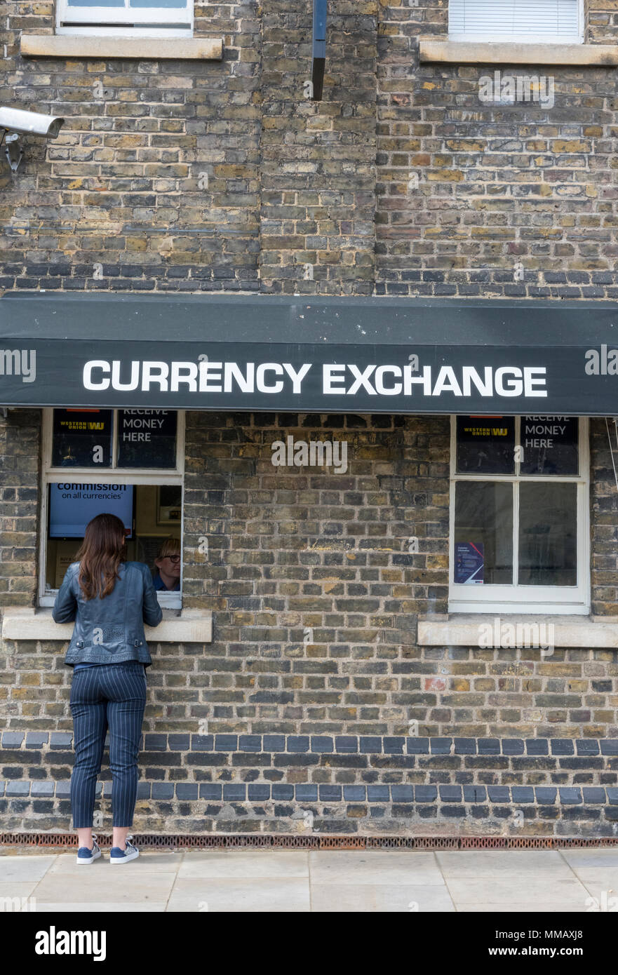 Eine junge Frau an der Theke einer Wechselstube oder Stand auf der Tower von London in der Stadt ändern Geld in englischen Pfund oder Euro. Stockfoto