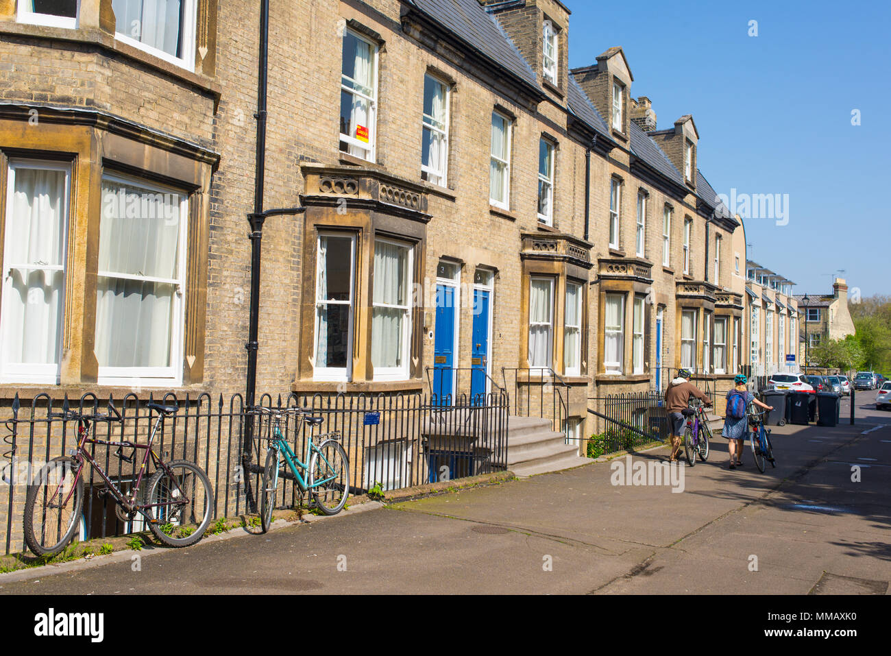 Cambridge, UK - April 2018. Die Leute von hinten zu Fuß in einer typisch britischen Straße mit klassischen englischen viktorianischen Häusern mit farbigen Türen an einem sonnigen Stockfoto