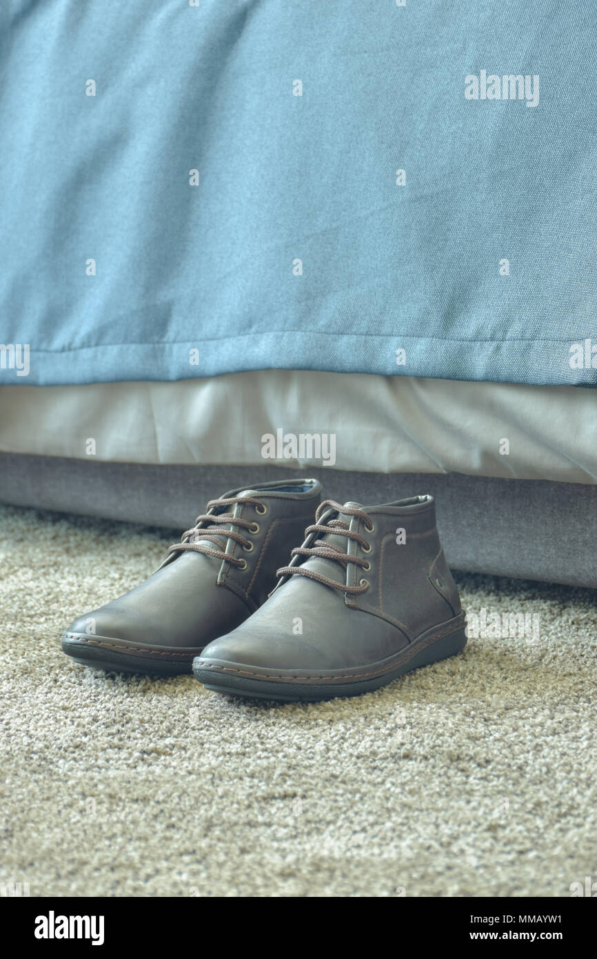Herren Schuh auf Teppich neben dem Bett Stockfoto