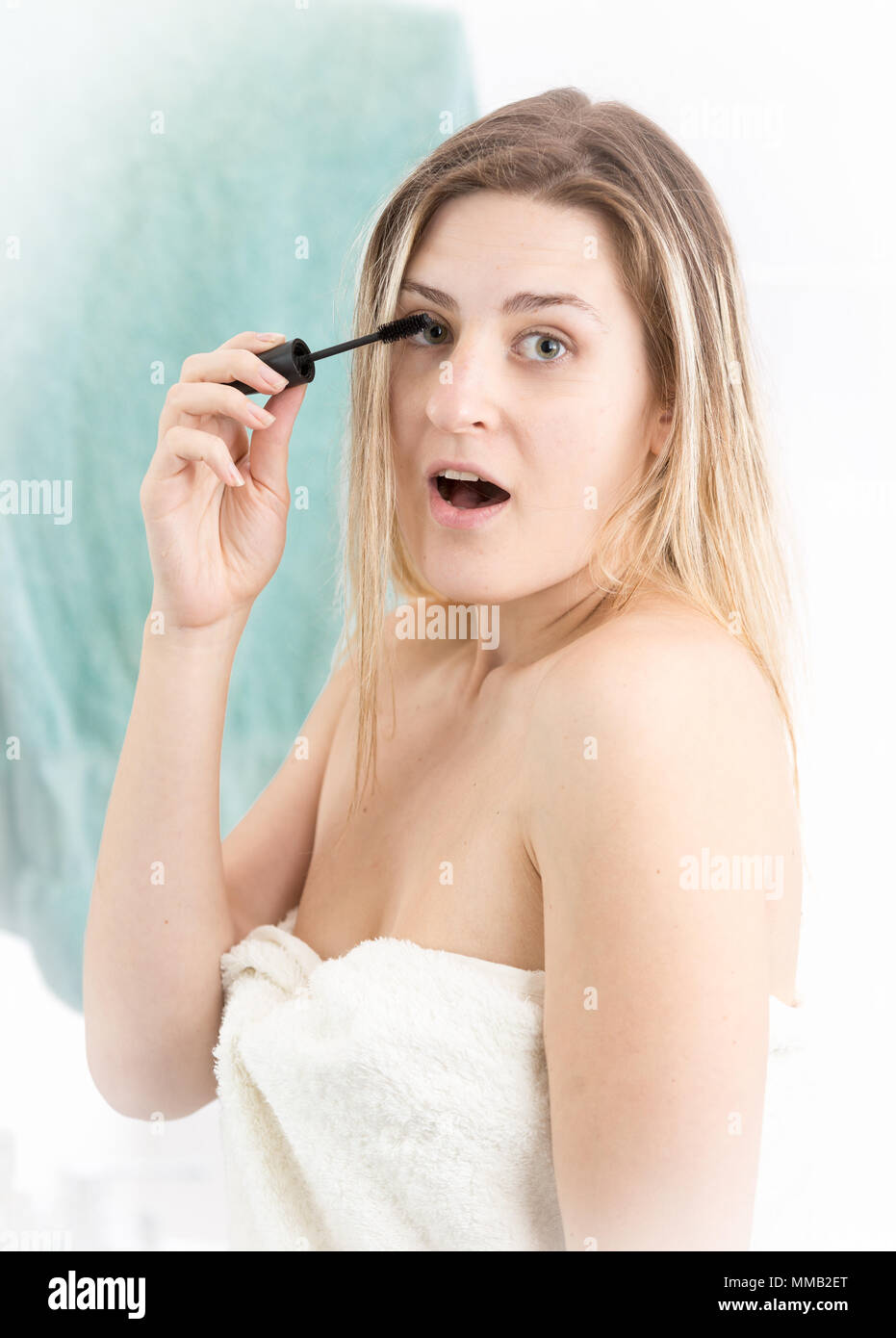 Porträt der jungen erstaunt Frau mit offenen Mund tun Make-up im Badezimmer Stockfoto