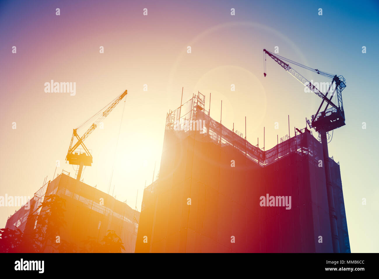 Kran mit im Bau Gebäude mit Sonnenuntergang Himmel. Anbau der städtischen U-industrielles Konzept. Stockfoto