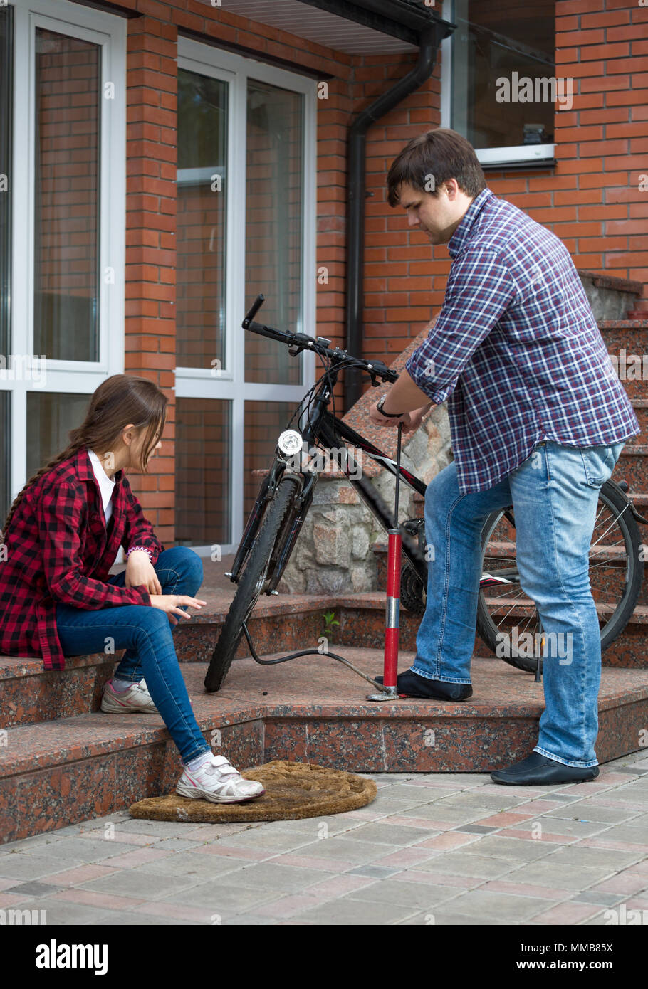 Junger Mann mit Tochter Reparatur Fahrrad und Pumpen Reifen Stockfoto