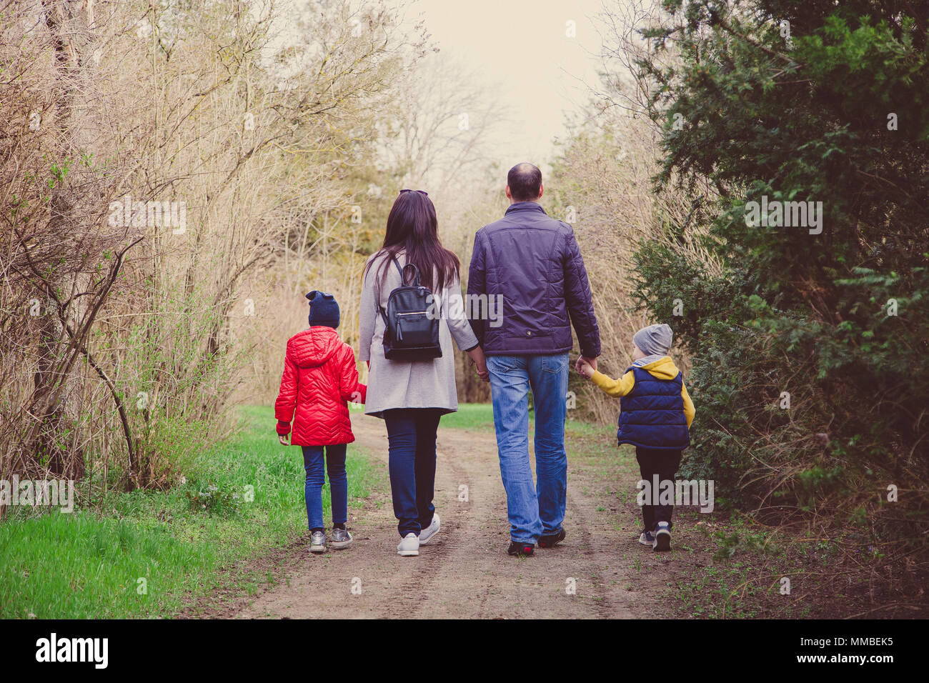 Glückliche junge Familie Ausgabe Zeit zusammen in der freien Natur. Die Eltern hält die Hände von kleinen Kindern. Stockfoto