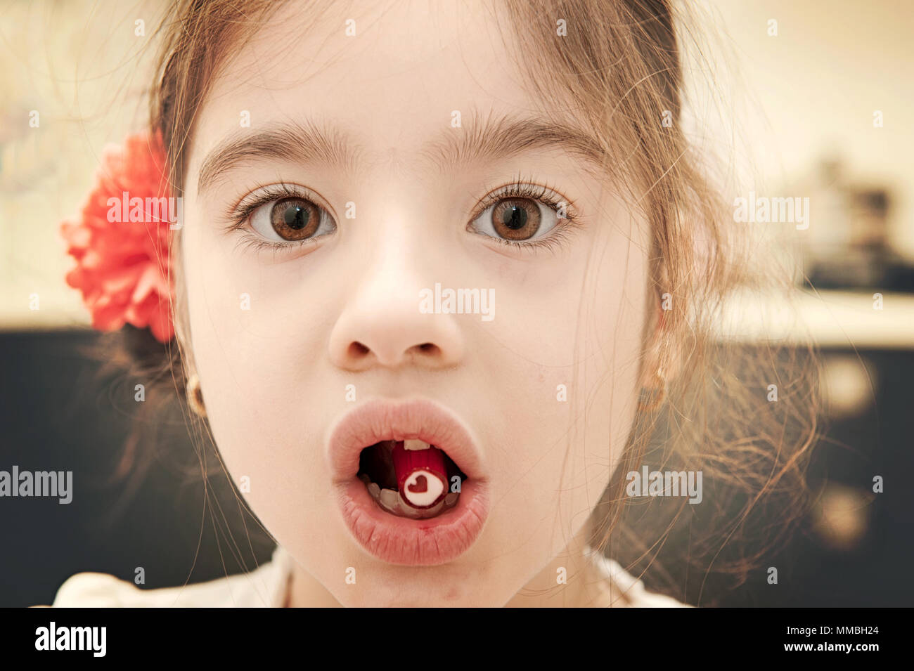 Kleines Mädchen holding Bonbons im Mund, Hard Candy mit roten Herzen Form, Istanbul Stockfoto