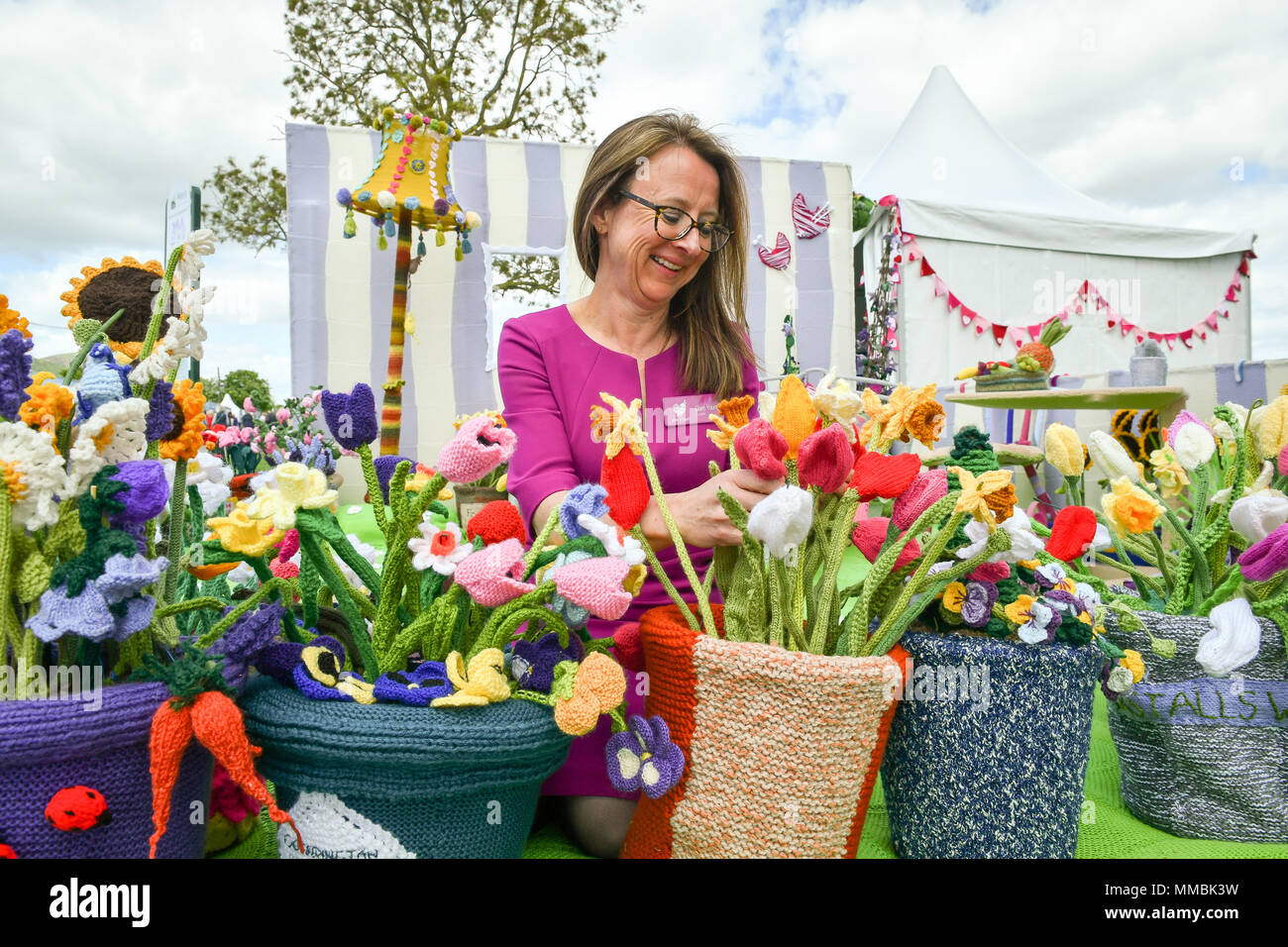 Clare Junge ordnet einen Topf mit verschiedenen gestrickt Blumen in der Arbeit des Herzens Garten', der weltweit erste gestrickt, Garten, während der Rhs Malvern Frühlingsfest an der drei Grafschaften Showground in Malvern, Worcestershire, von Clare Jungen als eine Hommage an ihren Ehemann Ken und das Hospiz, die für ihn gesorgt. Stockfoto