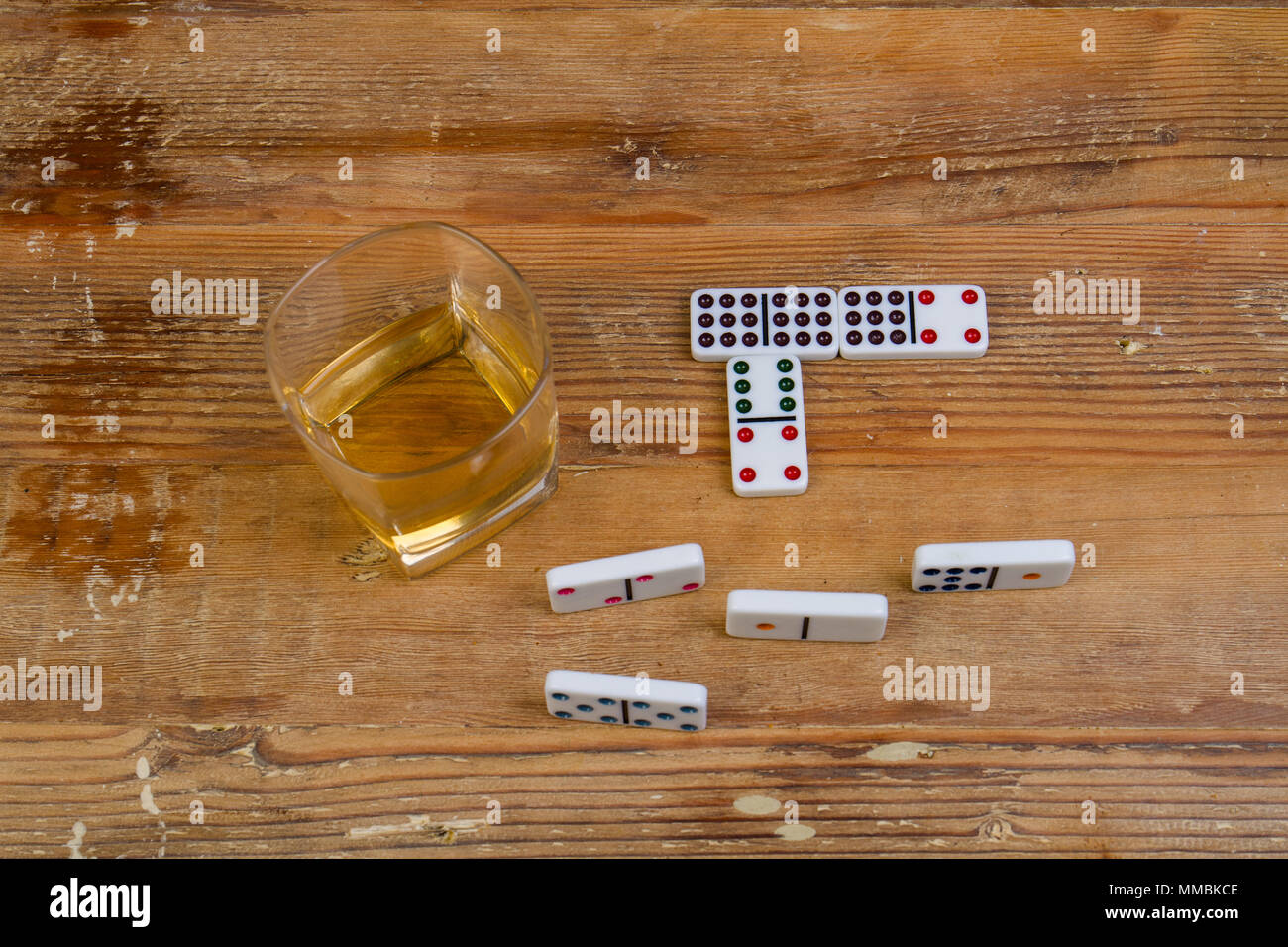 Glas Whisky und ein Spiel der Domino auf einem hölzernen Oberfläche Bild mit Kopie Raum im Querformat. Stockfoto
