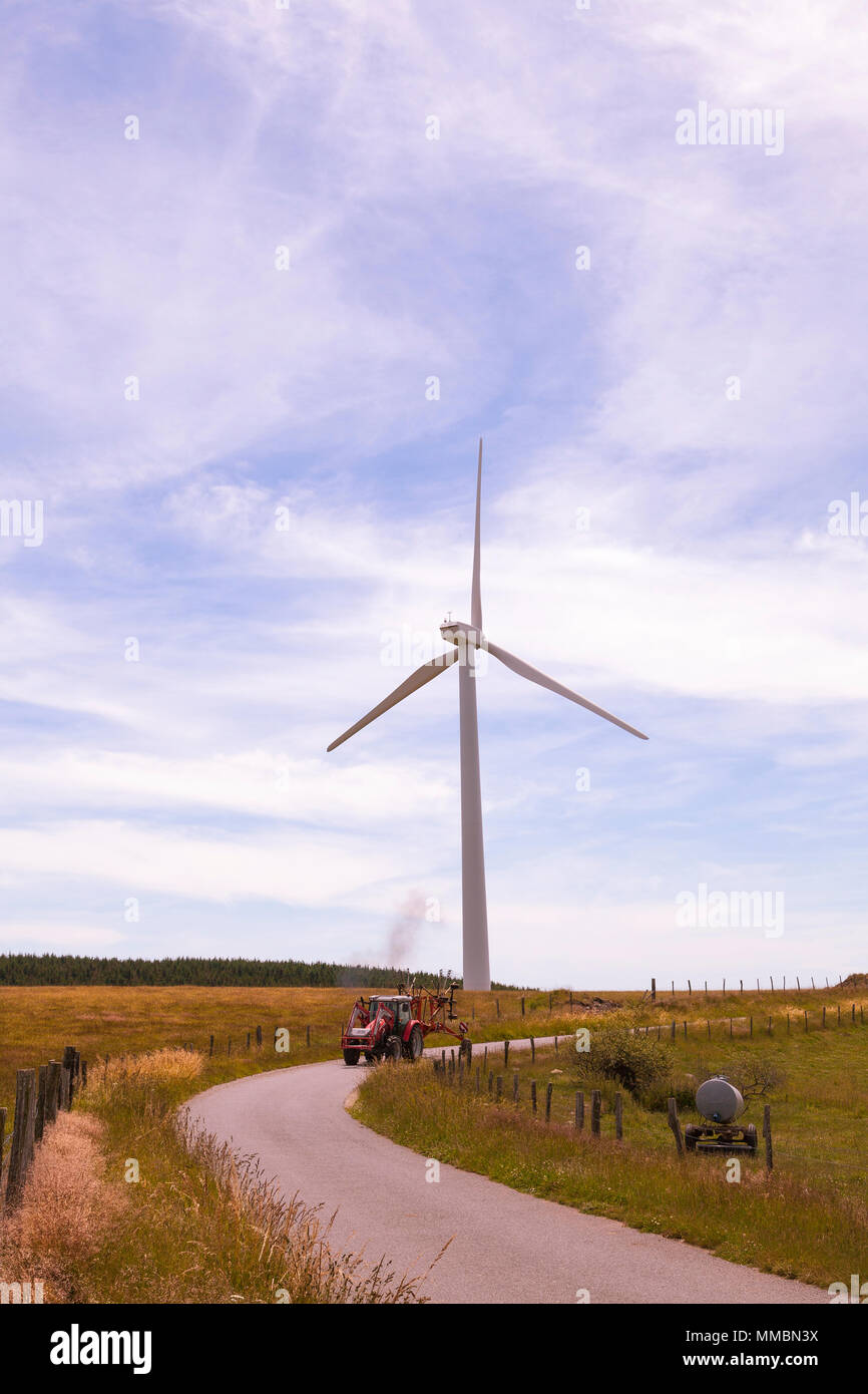 Landwirt homeward bound nach der Ernte Heu in der Dämmerung in seinem Traktor mit Rechen, eine Windenergieanlage, die renewble alternative Energie und Stromanteil über 22% liegt, Stockfoto