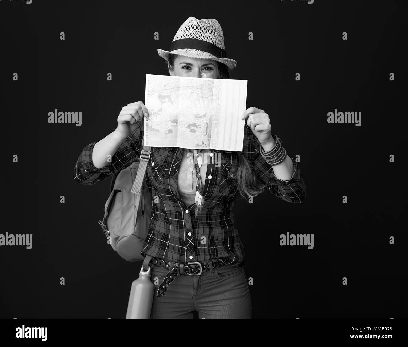 Auf der Suche nach inspirierenden Orten. Aktive reisende Frau mit Rucksack versteckt sich hinter Karte gegen Hintergrund Stockfoto