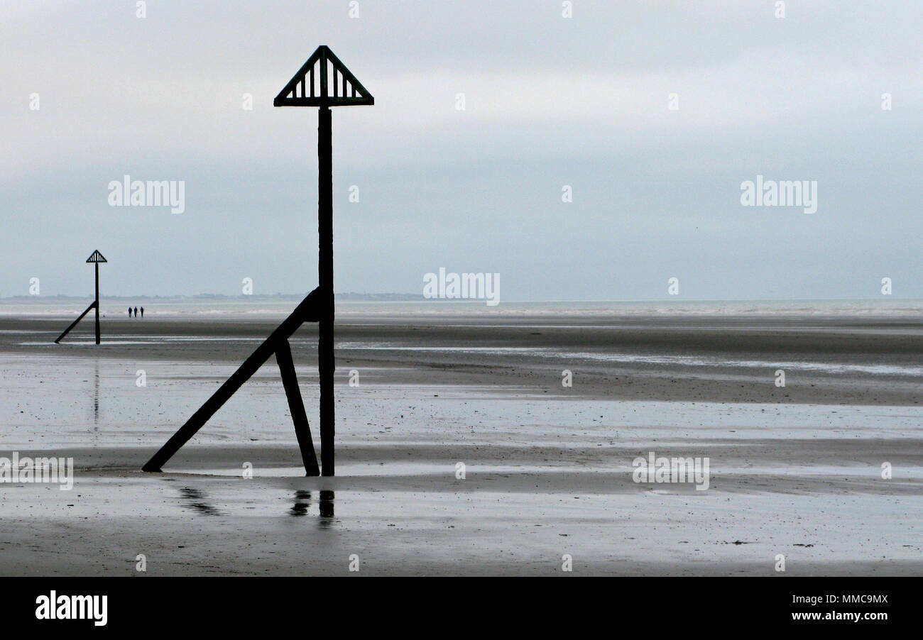 Ein Trio von fernen Wanderer auf dem großen flachen Strand an der Küste West WIttering, Sussex, England, UK, low tide durch die trübe winter Englisch am Meer Stockfoto