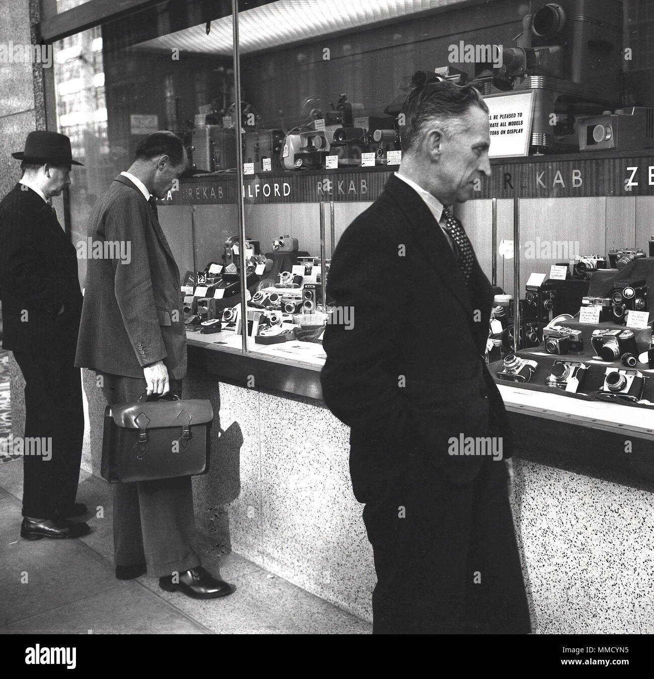 1960, London, Unternehmer bei der großen Bandbreite der fotografischen Film Kameras suchen auf Anzeige in einem Schaufenster. Stockfoto