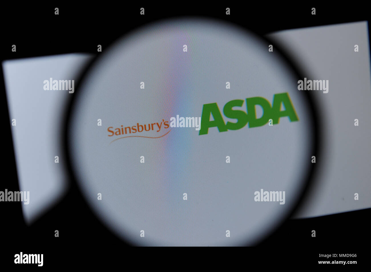 Die Sainsbury's und Asda Logos durch ein Vergrößerungsglas gesehen Stockfoto