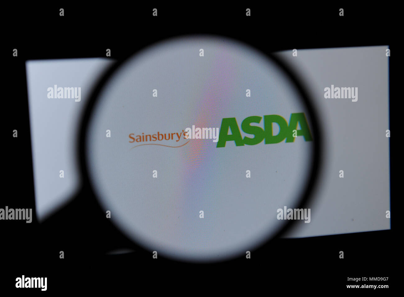 Die Sainsbury's und Asda Logos durch ein Vergrößerungsglas gesehen Stockfoto