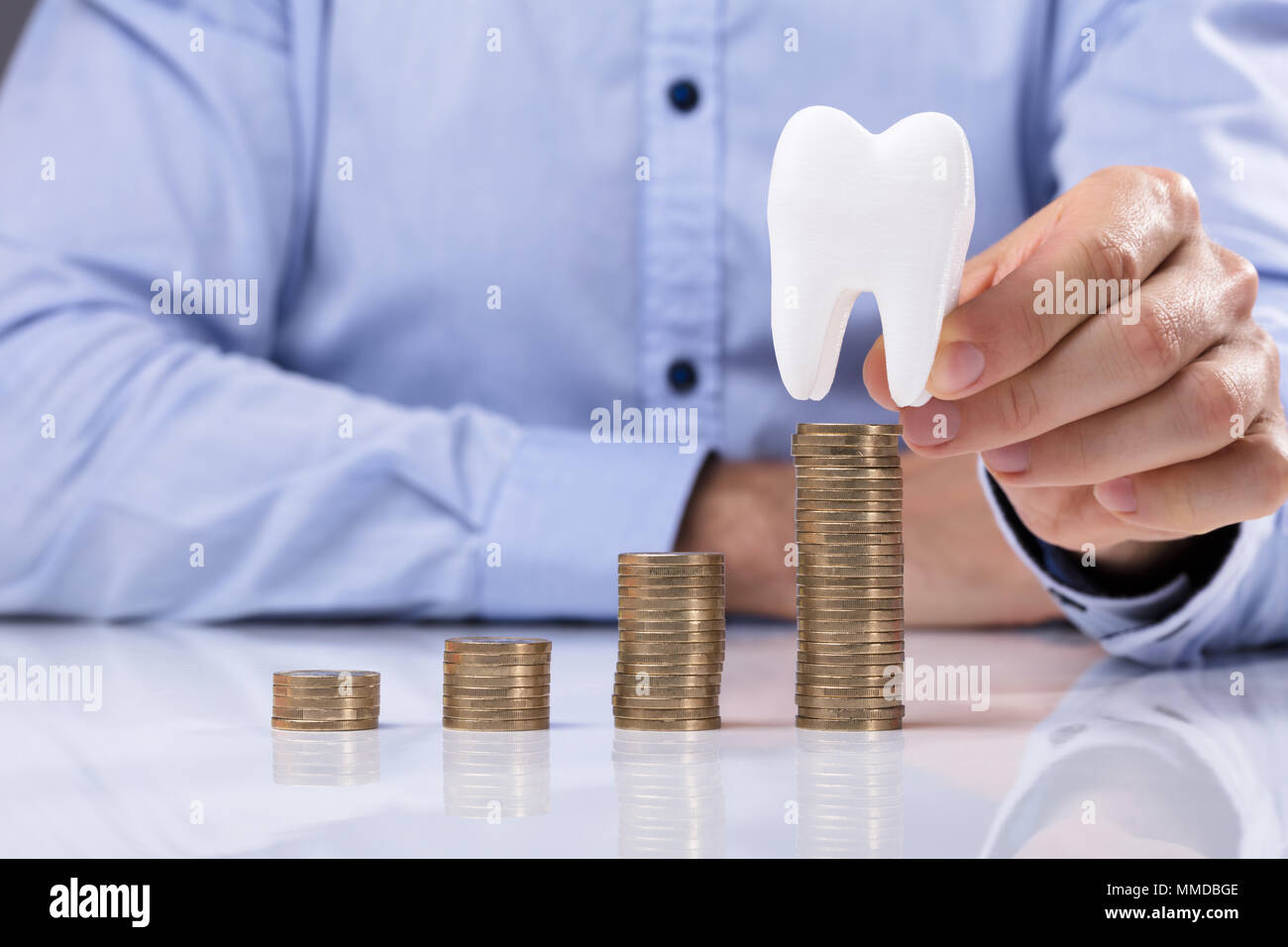 Mann die Münze auf dem Stapel Münzen Vor der Weißen Zahn Stockfoto