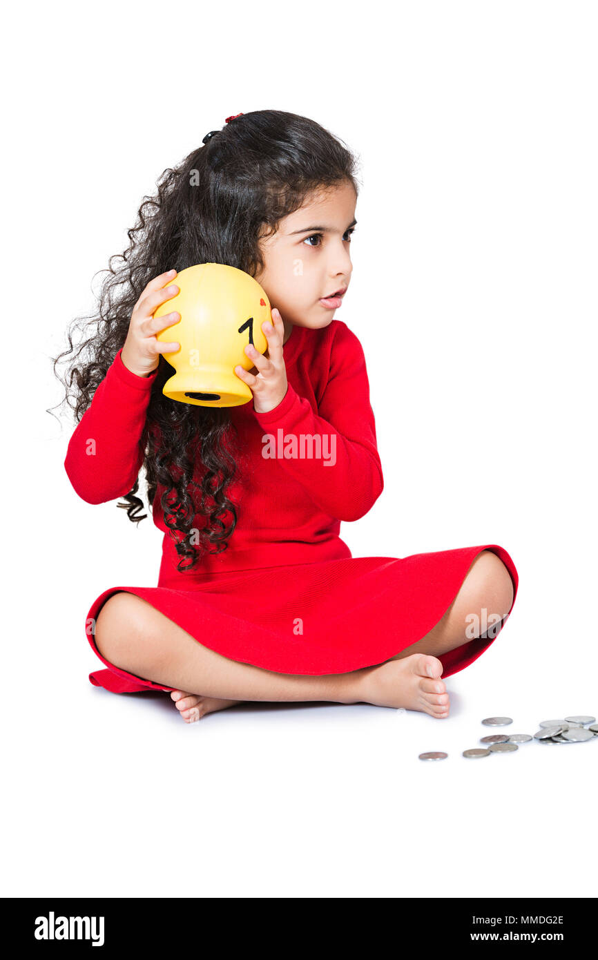 Ein Kind Mädchen sitzen, zu hören, wie viel Geld im sparschwein Stockfoto