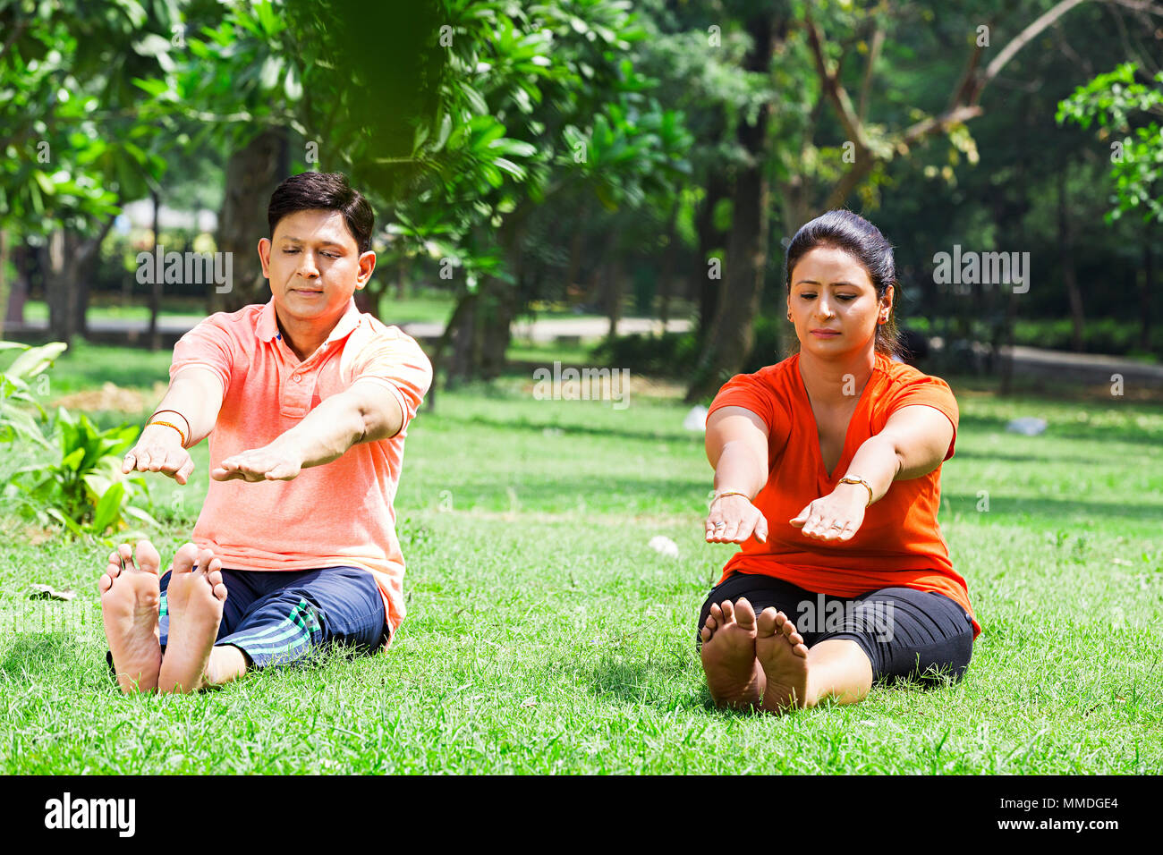 Zwei Married-Couple sitzen Gras Yoga Stretching Fitness Übung In-Garden Stockfoto