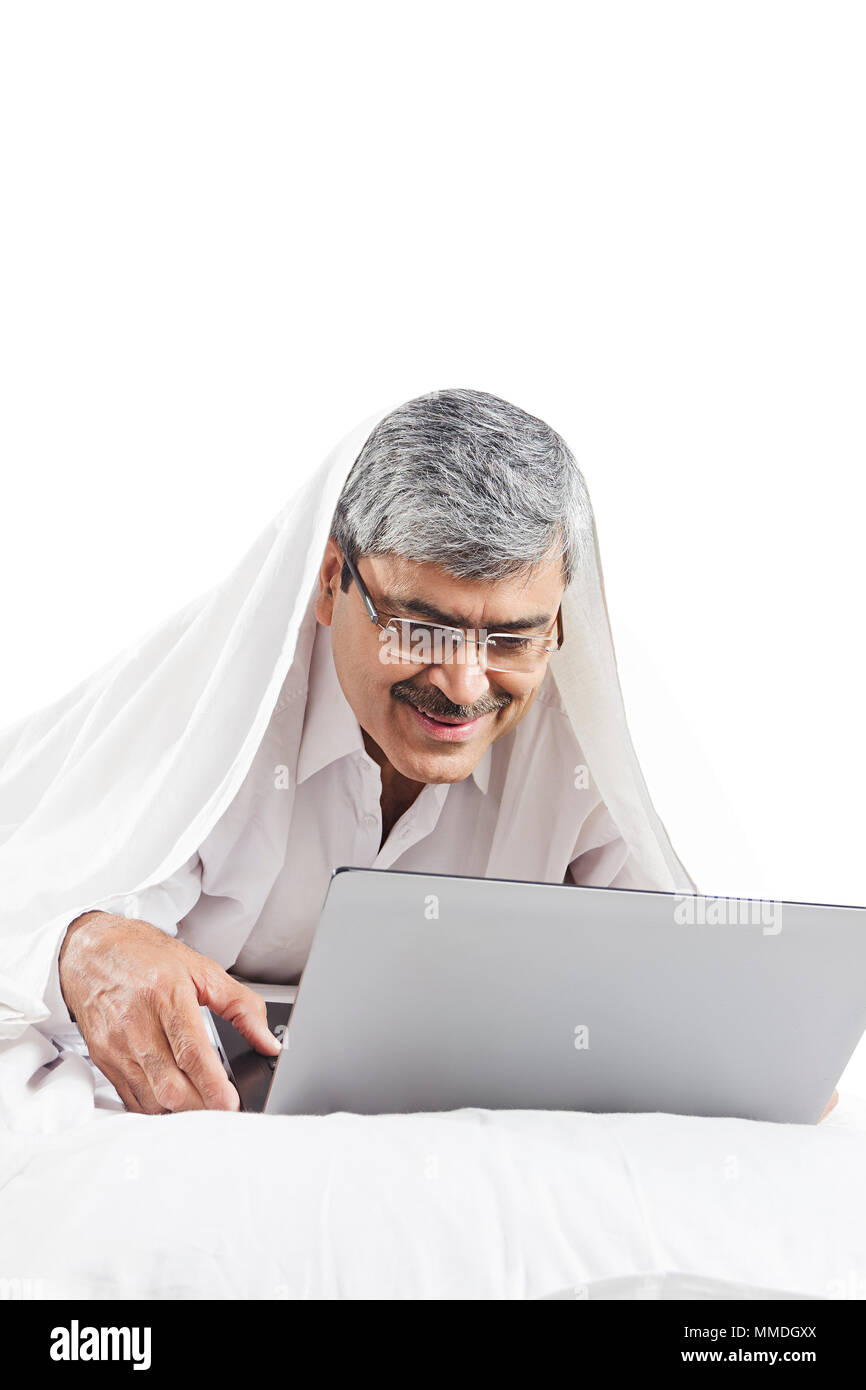 Lächelnd älterer Mann Lying-On-Bett Suche Laptop Bildschirm arbeiten Schlafzimmer Vor-Ort-Service Stockfoto