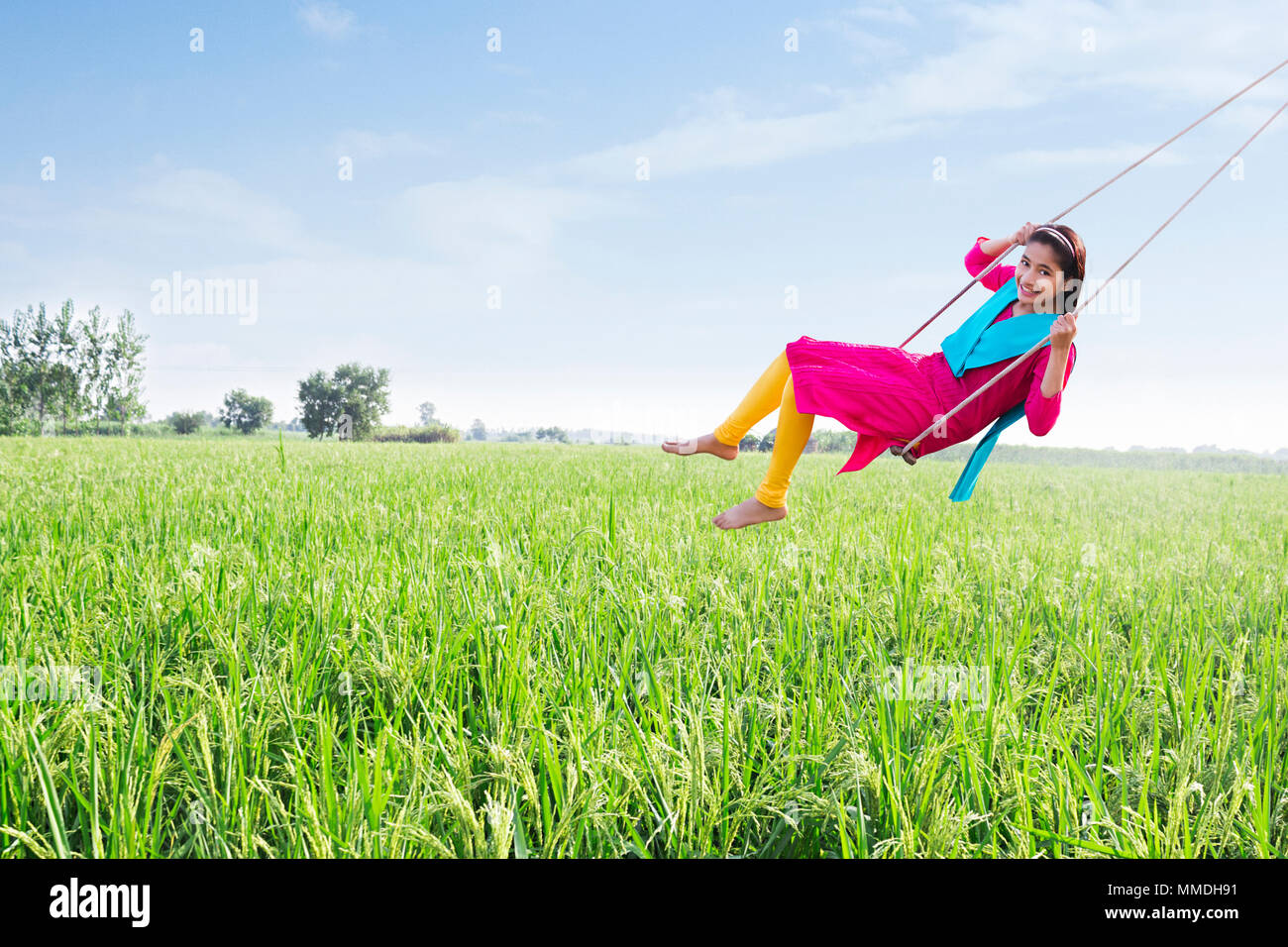 Lächelnd eine ländliche Junge Mädchen spielen Schwingen schwingen Seile Feld Stockfoto