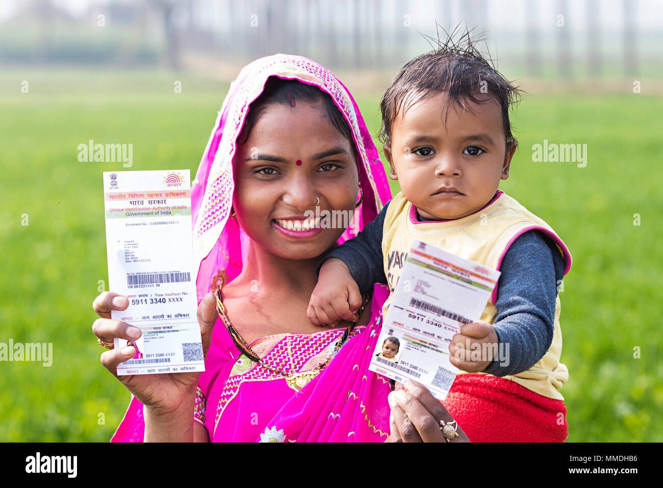 Lächelnd ländlichen Mutter und Kind Sohn zeigen Aadhaar Karte Bauernhof Stockfoto