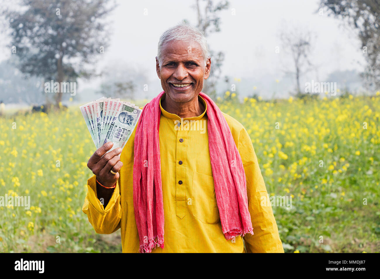 Eine ländliche Dorfbewohner Senior-Man Geldhaltung Rupee Notizen im Feld Dorf Stockfoto
