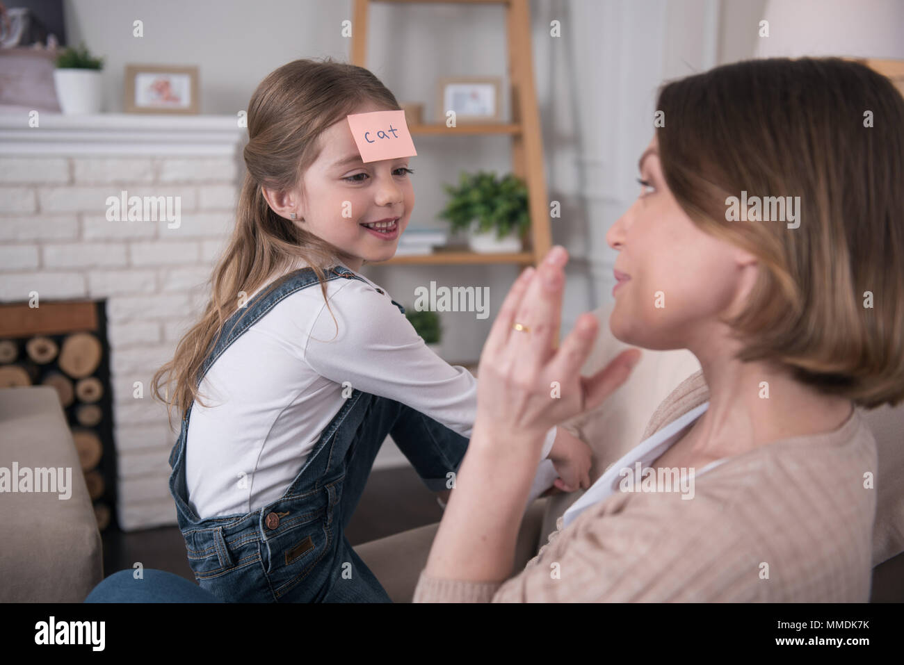 Vergnügtes Mädchen spielen ein Spiel mit ihrer Mama Stockfoto