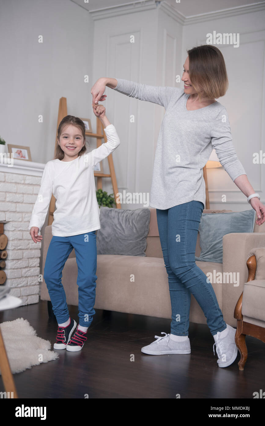 Überschäumende Mädchen tanzen mit ihrer Mama Stockfoto