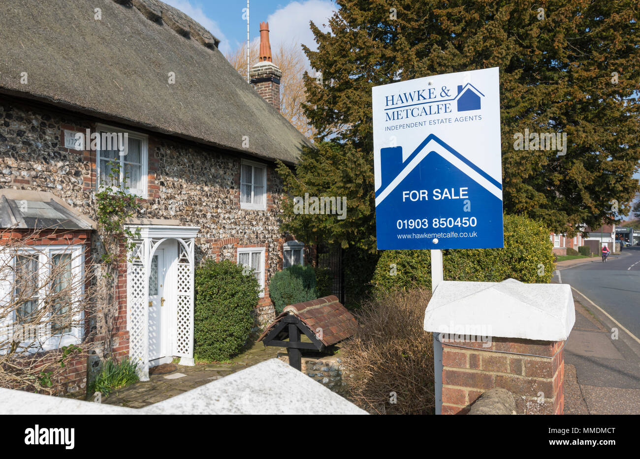Für Verkauf Zeichen von Hawke & Metcalfe Immobilienmakler ein Haus für Verkauf in einem Dorf in England, Großbritannien. Stockfoto
