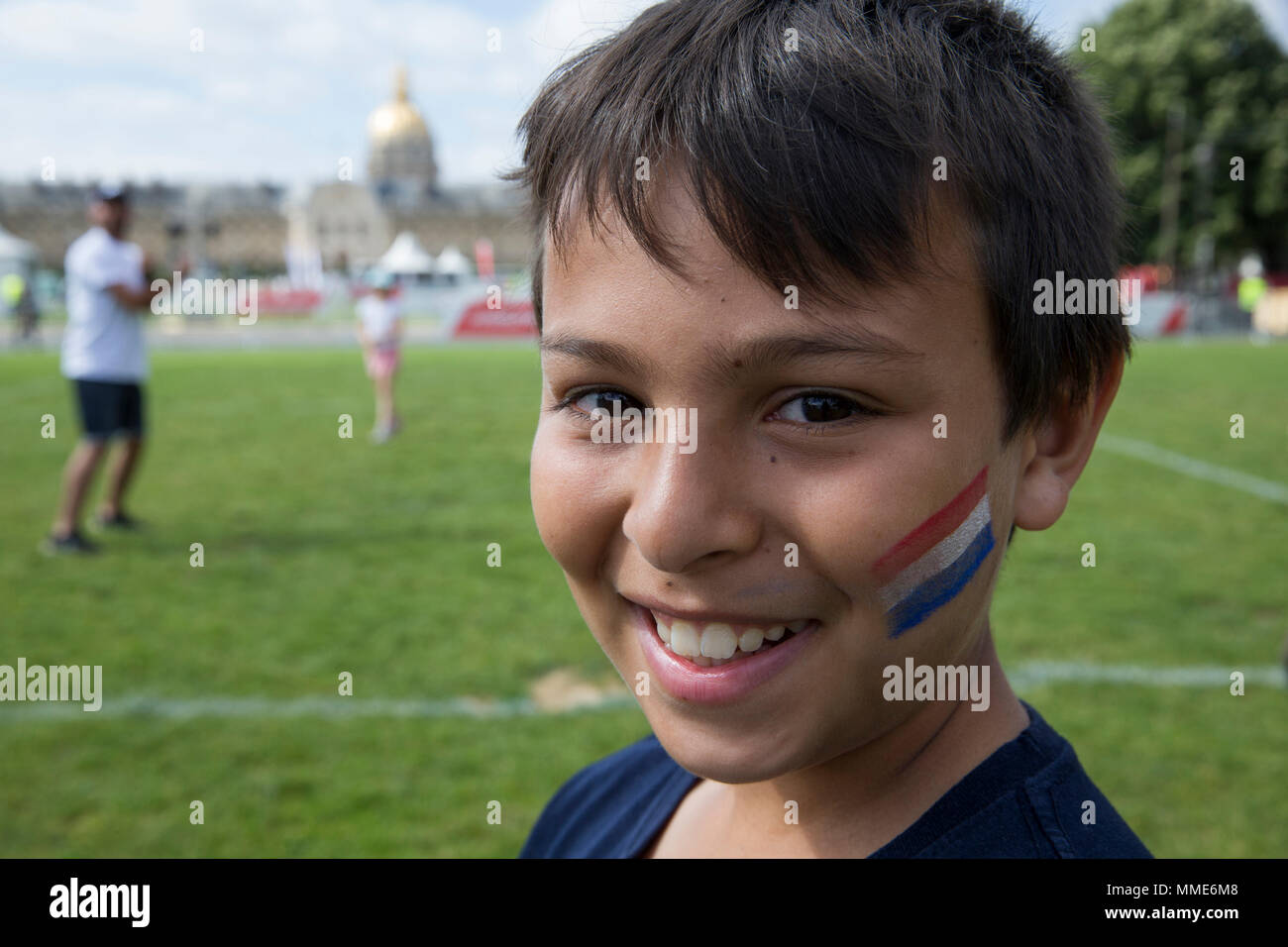 Ein Lächeln auf den 11-jährigen Jungen mit einem Französischen Flagge tatoo. Paris, Frankreich. Stockfoto