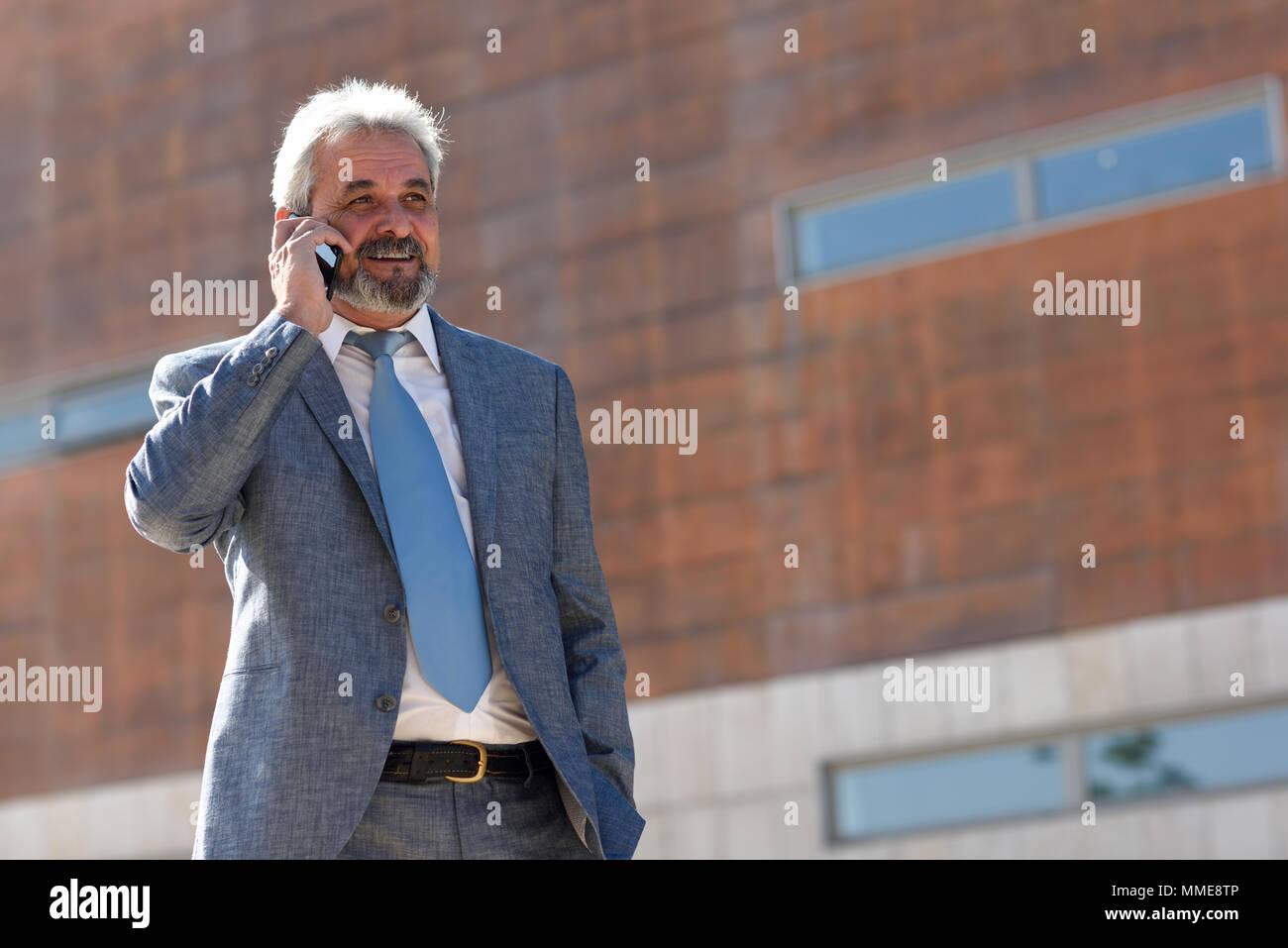 Portrait eines älteren Geschäftsmann im Gespräch mit einem Smart Phone außerhalb der modernen Bürogebäude. Erfolgreicher Geschäftsmann im städtischen Hintergrund. Stockfoto