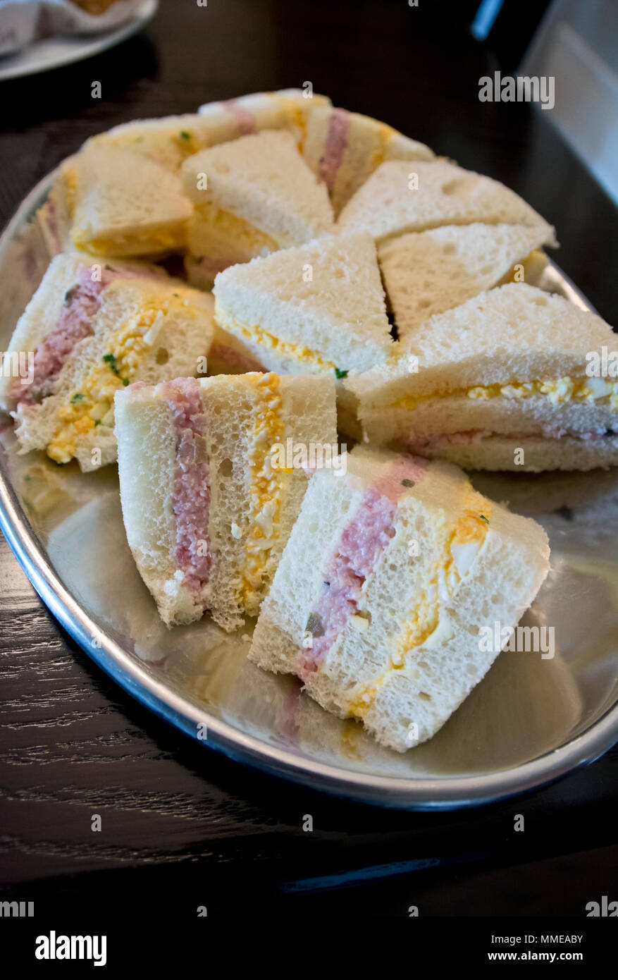 Crustless Sandwiches mit Ei, Salat und gehacktem Schinken auf einem Teller. Stockfoto