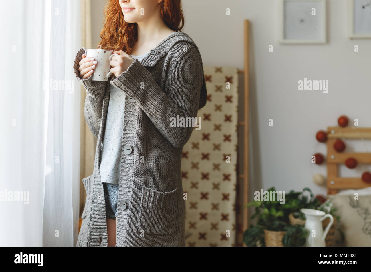 Lächelnde Frau in Pullover Blick durch das Fenster Stockfoto
