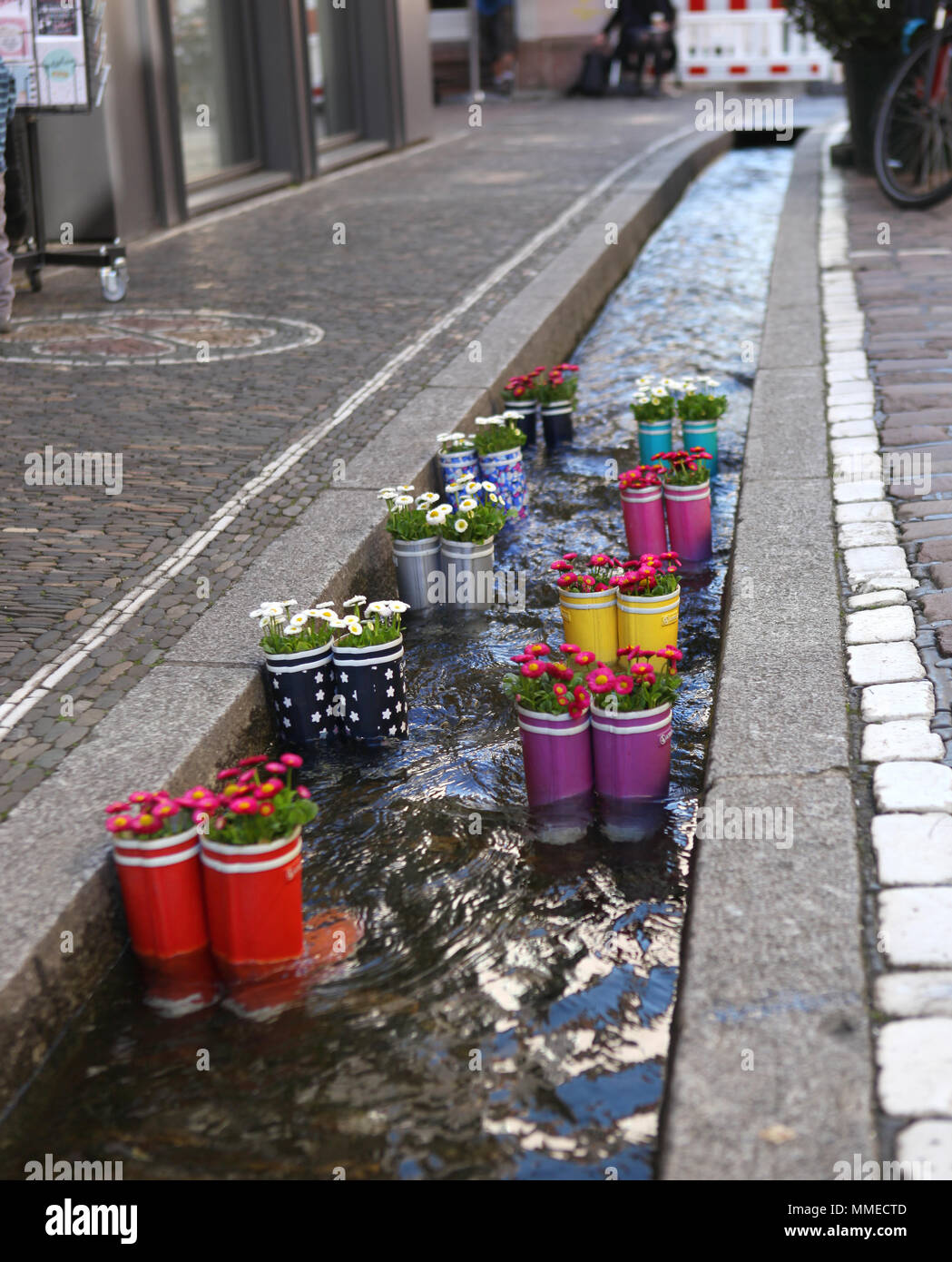 Gummistiefel im Wasser mit Blumen in der Stadt Freiburg. Touristische Attraktion. Stockfoto