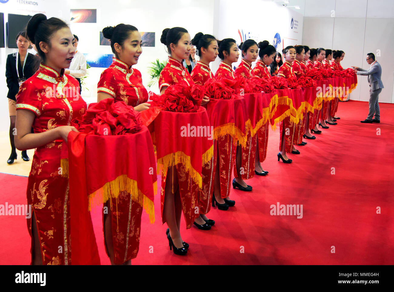 Chinesische Frauen in traditionell gestalteten roten Kleidern Form einer Präsentation Line-up in Beijing, China. Stockfoto