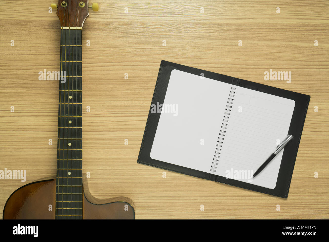 Akustische Gitarre und Notebook auf Holz Hintergrund. Ansicht von oben. Stockfoto