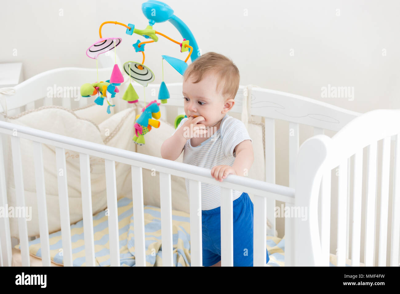 10 Monate altes Kleinkind Junge in weißem Holz Kinderbett Stockfoto