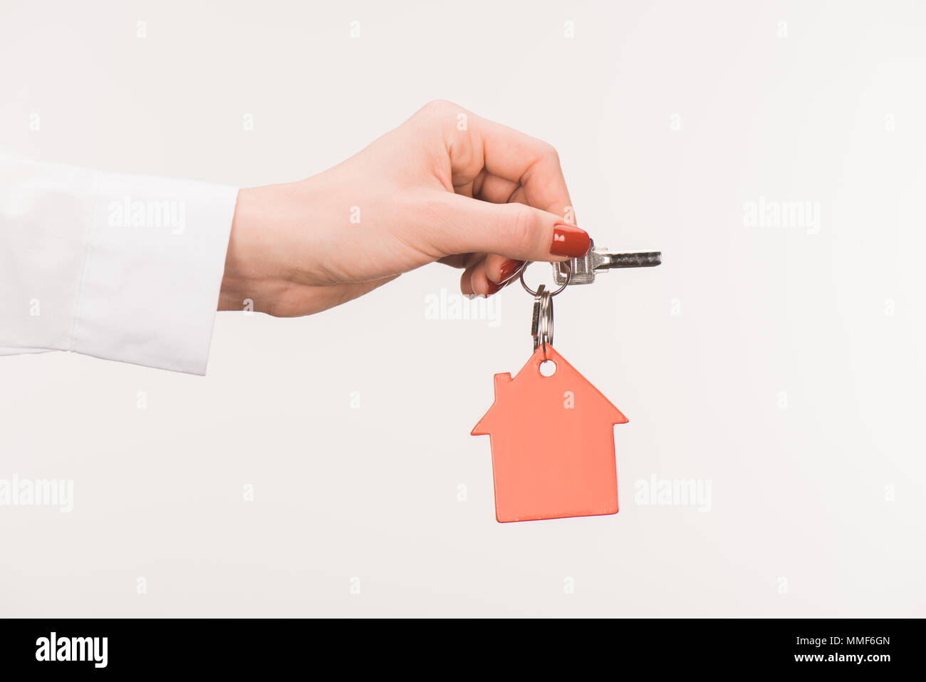 Zugeschnittenes Bild der weiblichen Hand Schlüssel vom Haus isoliert auf weiss Stockfoto