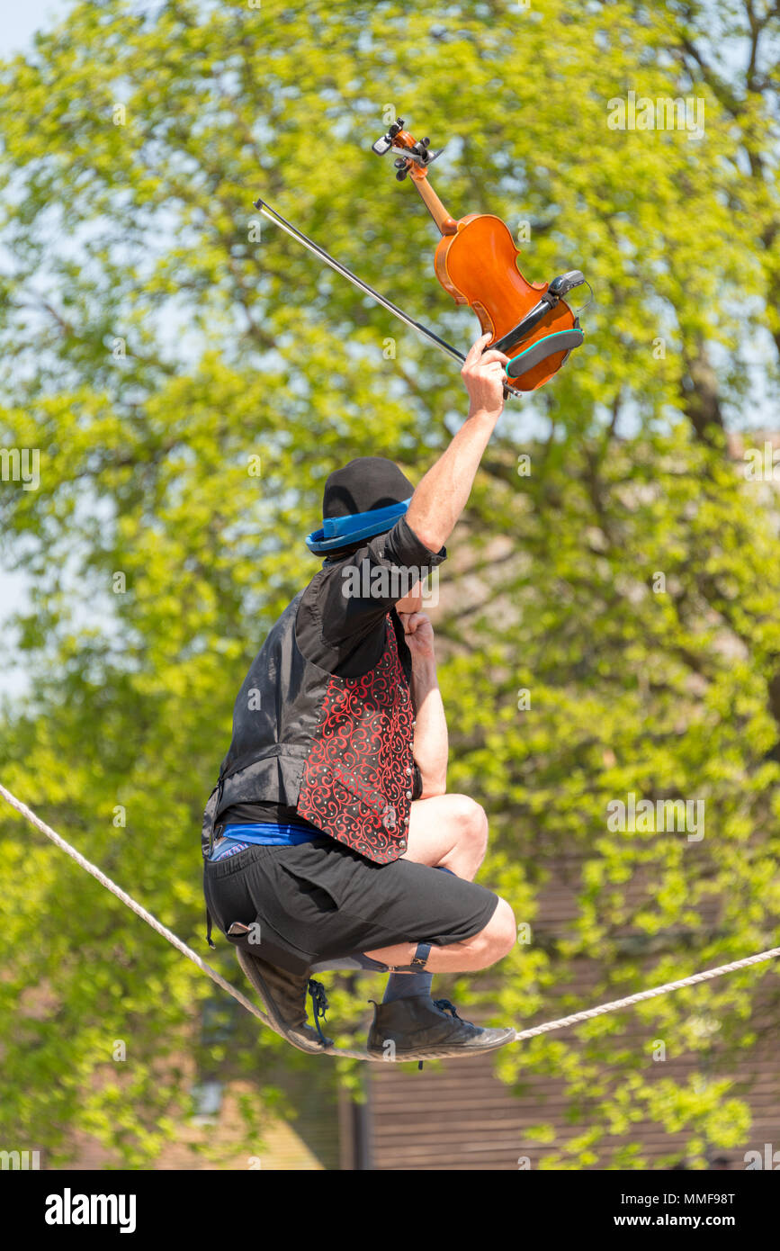 Street Performer walking Seil und spielen Geige mit Baum im Hintergrund Stockfoto