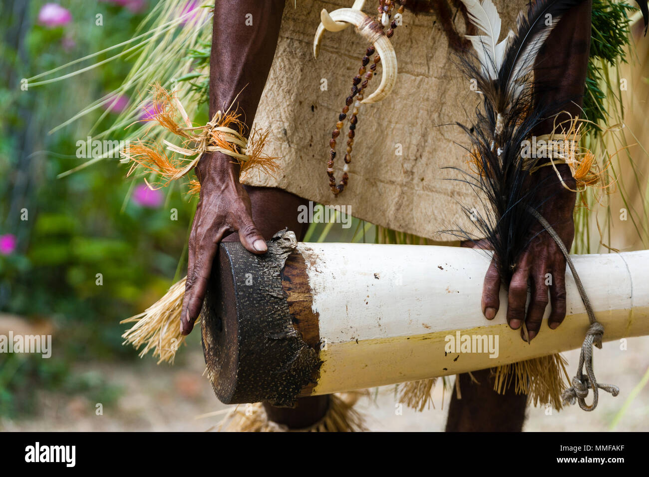 Eine Samarai Krieger tragen ein Gras und Rinde Rock spielen ein Reptil Haut in einem Tribal Zeremonie drum. Stockfoto