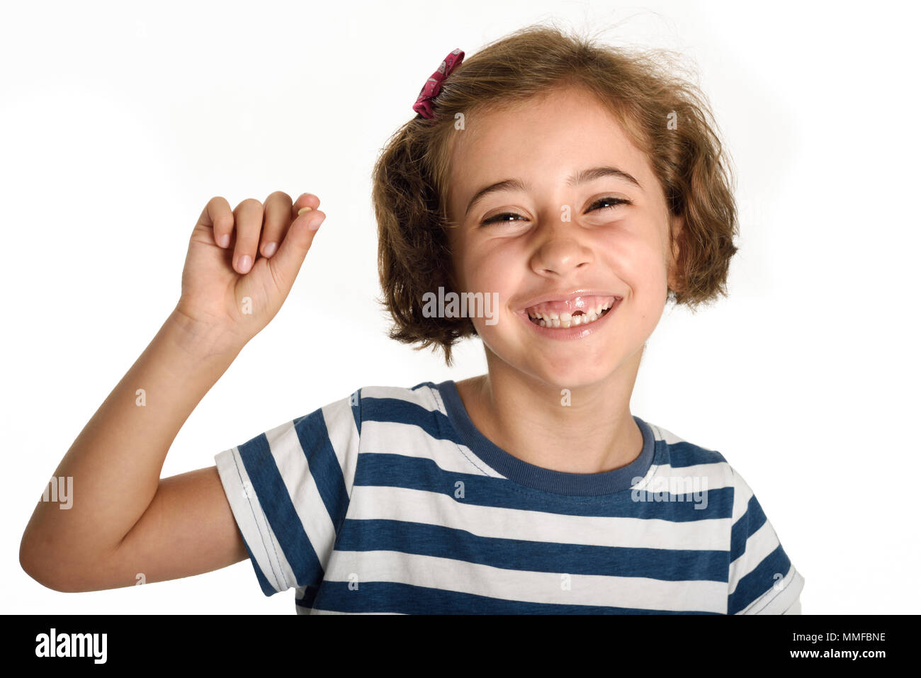 Glückliche kleine Mädchen ihren ersten gefallenen Zahnes angezeigt. Lächelnd kleine Frau mit einem schneidezahn in ihrer Hand. Isoliert auf weißem Hintergrund. Studio gedreht. Stockfoto