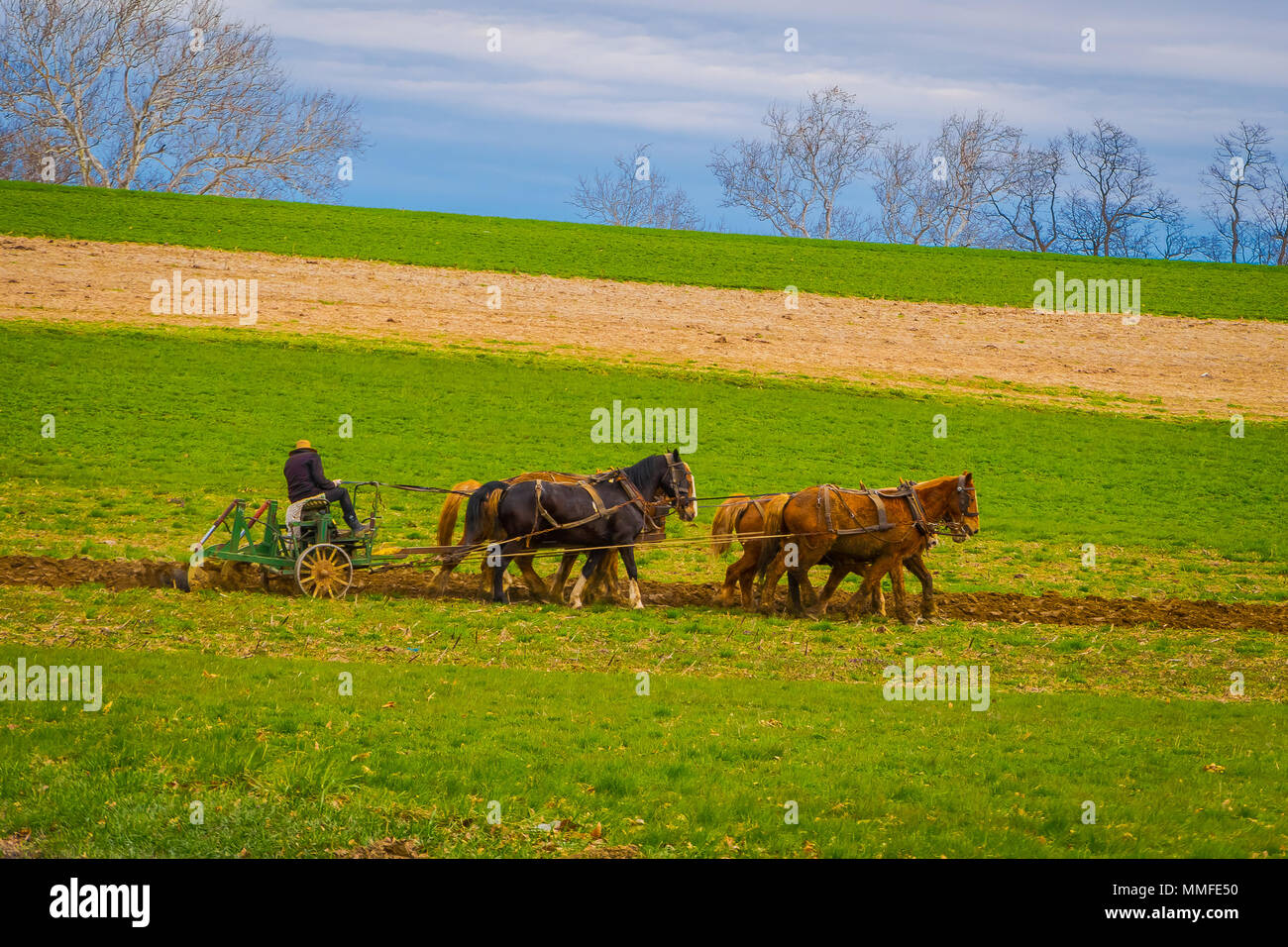 LANCASTER, USA - April, 18, 2018: Im Freien von nicht identifizierten Amish Landwirt mit Pferden zu den antiken Pflug auf dem Feld. Sie ihre eigene Nahrung ohne Technologie produzieren Stockfoto
