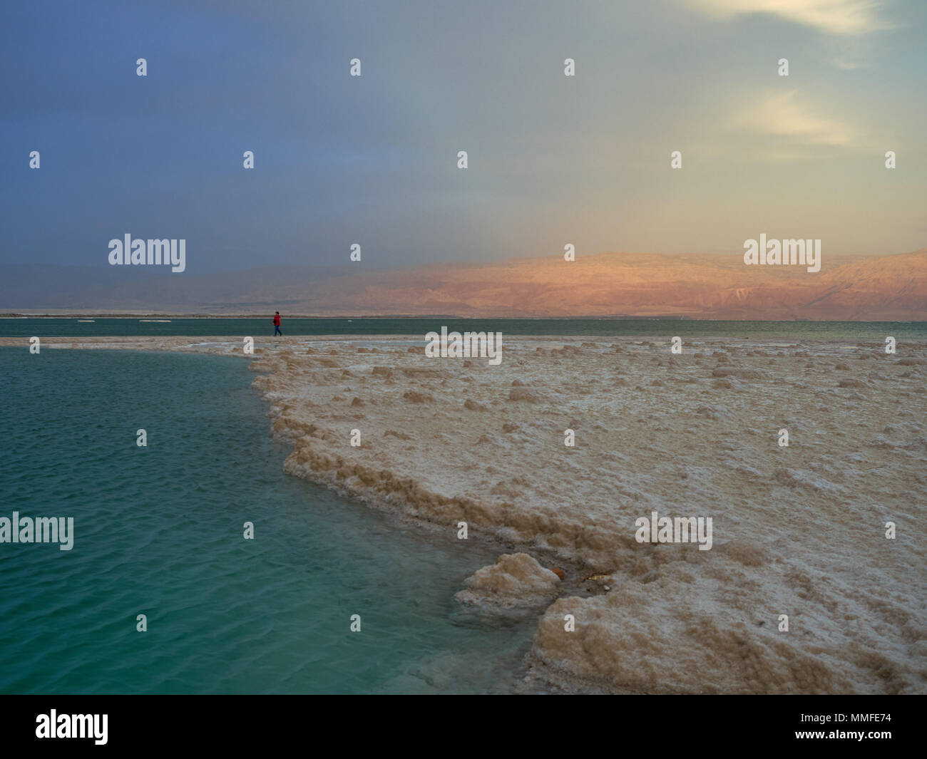 Totes Meer, rechts türkis Salz, Wasser, auf der rechten Seite ist eine salzige Kruste von Sushi, im Hintergrund ist eine kleine Abbildung eines Mannes, Israel. Stockfoto