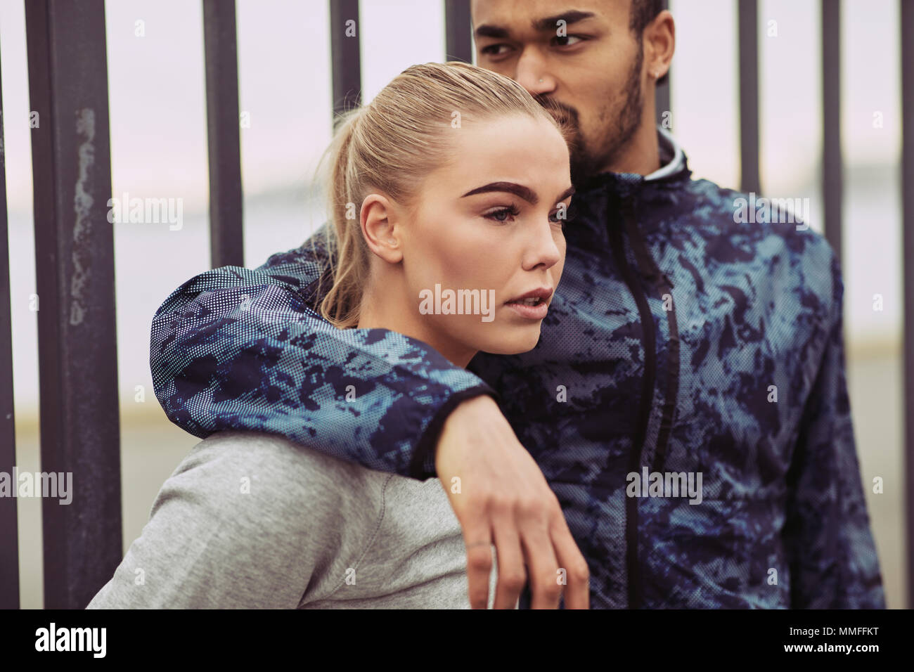Junger Mann in Sportswear steht mit seinen Arm um seine Freundin während einer Pause zusammen aus einem Lauf Stockfoto